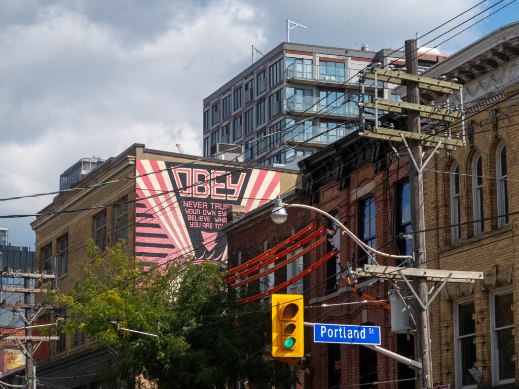 Image taken of buildings surrounding a mural made by street artist Shepard Fairey between Portland Street and Queens Street West in Toronto.,