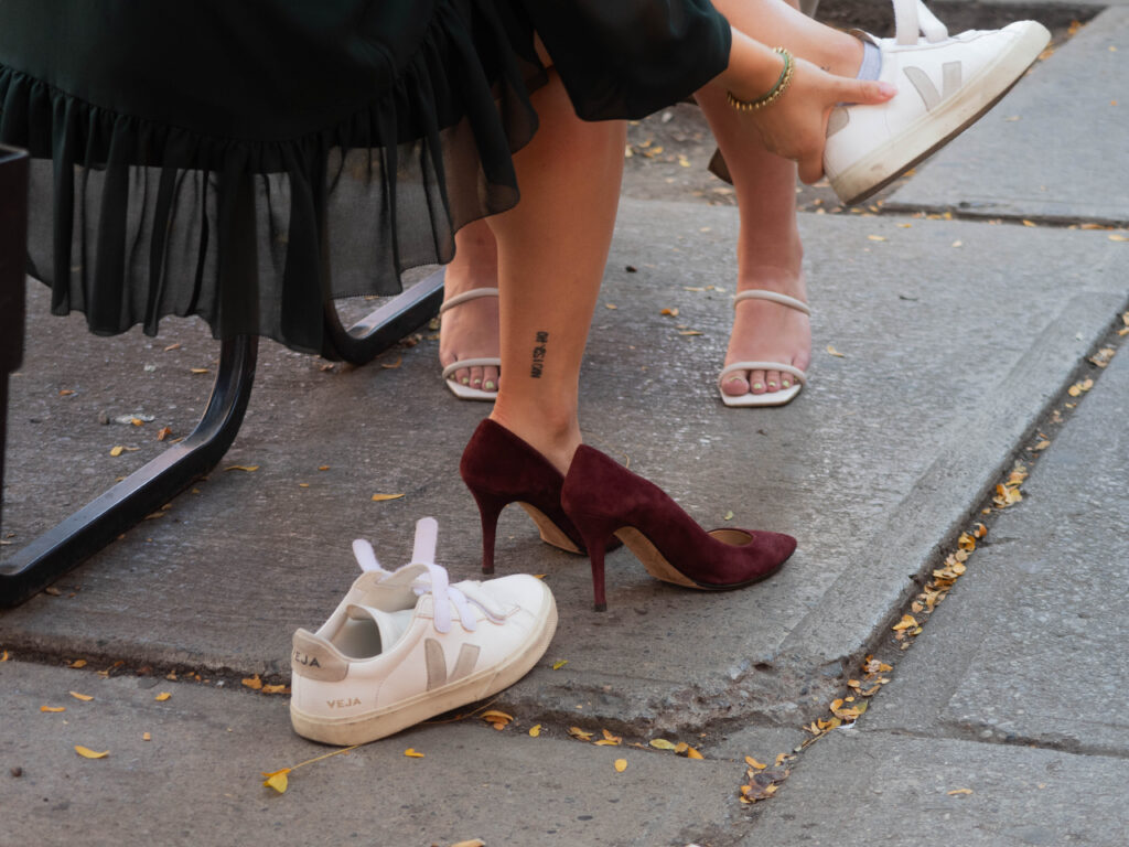 Woman taking off white snakes and putting on maroon suede heels